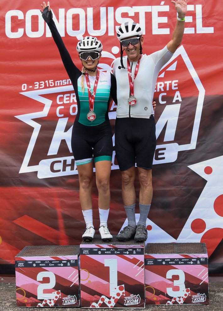 Ciclistas en el podio del KOM Challenge con el rótulo Conquisté el KOM